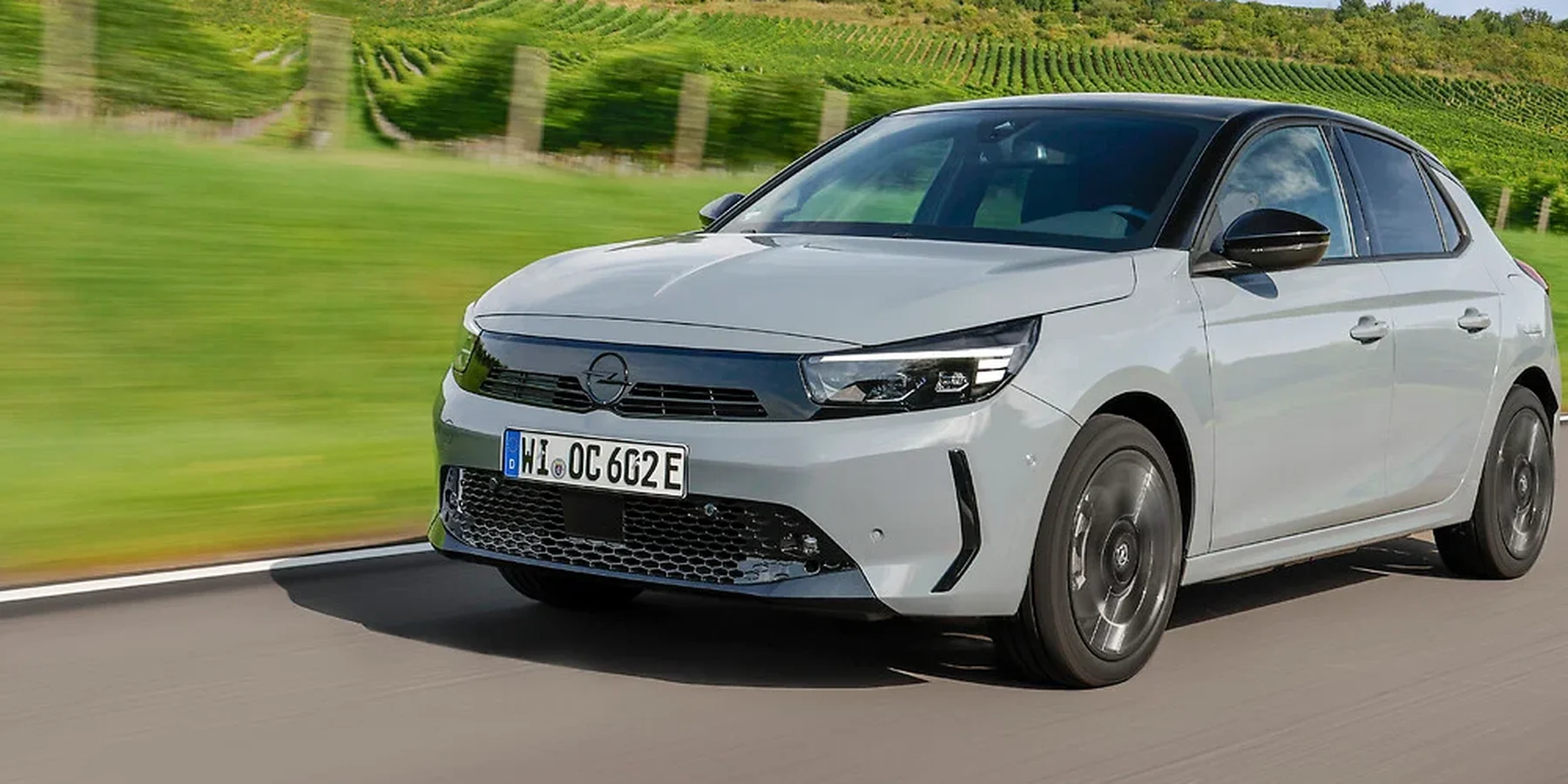 Opel Corsa w kolorze szarym na drodze wśród winnic