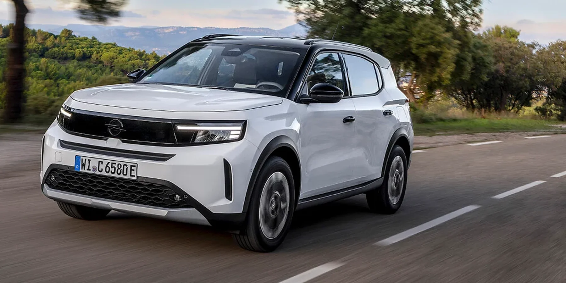Opel Frontera w kolorze białym na drodze wśród drzew